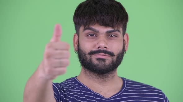 Face of Happy Young Overweight Bearded Indian Man Giving Thumbs Up alt