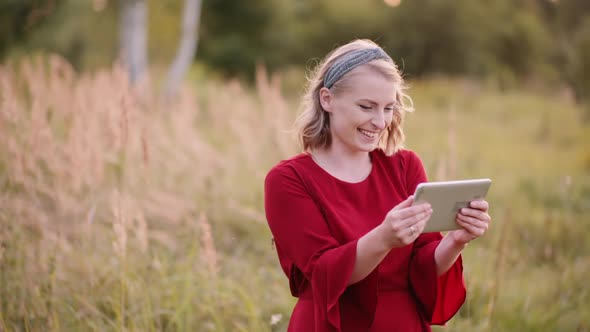 Smiling Woman Using Digital Tablet Outdoors in Summer alt