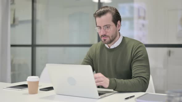 Young Businessman Working on Laptop in Office alt