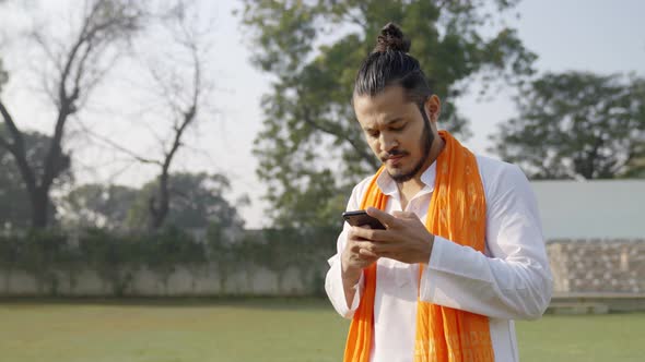 Indian man using smartphone in a traditional Indian outfit alt