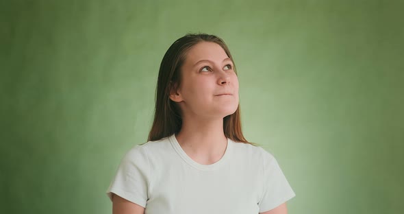 Dreamful Model Looks Upward and Bites Lips Posing on Green alt