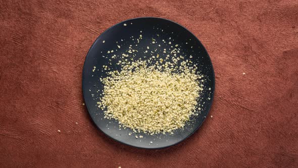 Hemp seed hearts are falling into black ceramic plate alt