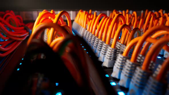Countless orange cables in a  server cabinet lit by a single spotlight. 4KHD alt