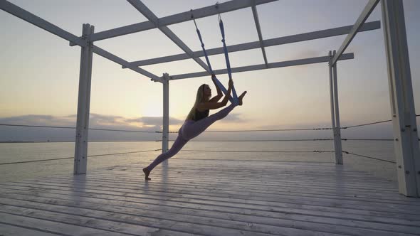 Woman in Tracksuit Does Legs Split Leaning on Hanging Sling