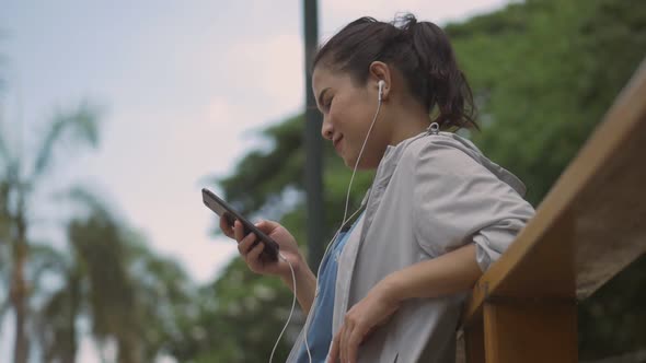 Portrait beautiful young Asian woman fitness runner using mobile phone.