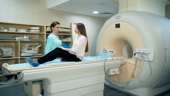 Young woman doing mri procedure in modern clinic. Female patient lying on a medical table machine  alt