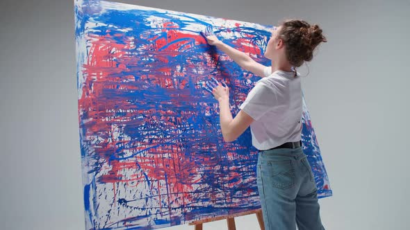 Young Woman Artist Draws with Her Hands on a Large Canvas in a White Room a Talented Artist Draws a alt