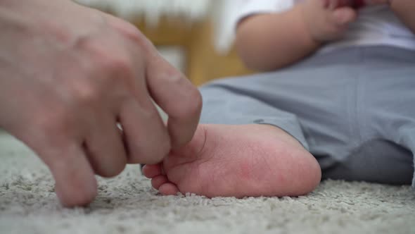 Parent Touching and Playing with Baby Boy Child Feet at Home with Love and Caring alt