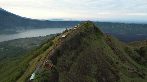 aerial over Mount Batur volcano with tourists standing on a ridge in Bali Indonesia alt