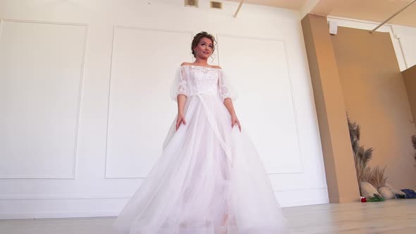 A Girl in a White Wedding Dress Poses Rotates the Hem alt