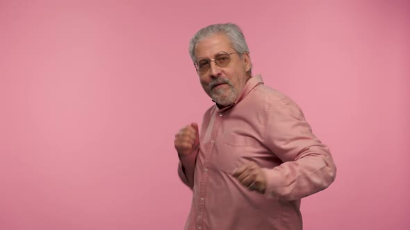 Portrait of an Elderly Man with Glasses Dances Funny Dance of Joy or Good Mood alt