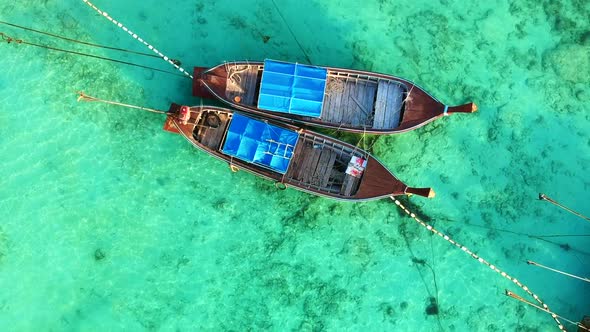 A zooming in shot of a Thai Long Tail boat while boat are dock from above with no people in the boat alt