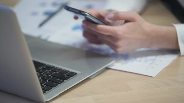 Female Manager Viewing Graphics on Smartphone in Office, On-Line Application alt