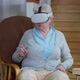 Absorbed Caucasian Senior Woman in VR Headset Gaming Online Sitting at Home in Living Room