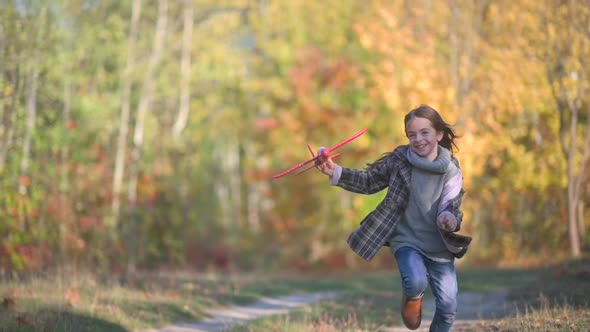 Happy Cute Girl Runs and Launches Model Airplane in Autumn Park.