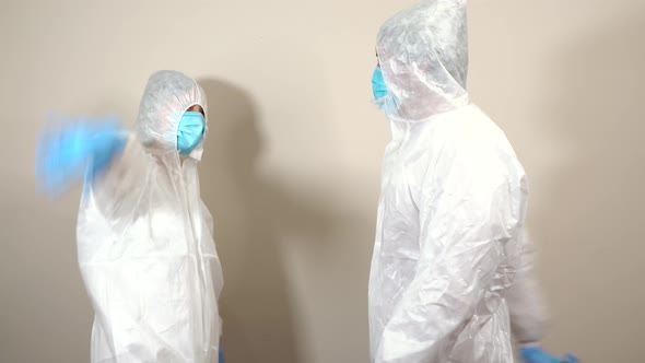 doctors in protective suit ppe greet each other animated with fists, joke while talking and say good alt