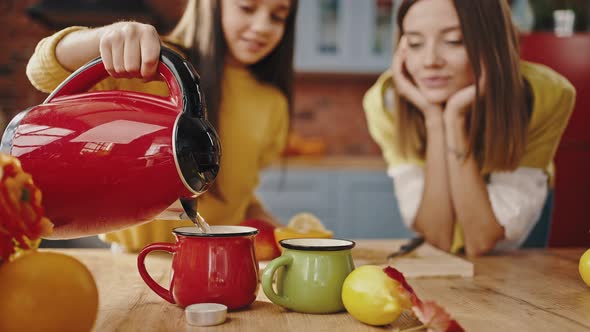 Kid Girl Pouring Boiling Water From Kettle Into Cups Making Tea in Kitchen at Home alt