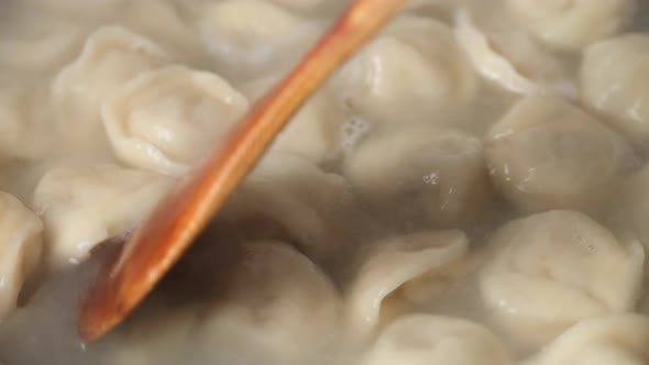 cooking dumplings. stir the dumplings with a wooden spoon alt