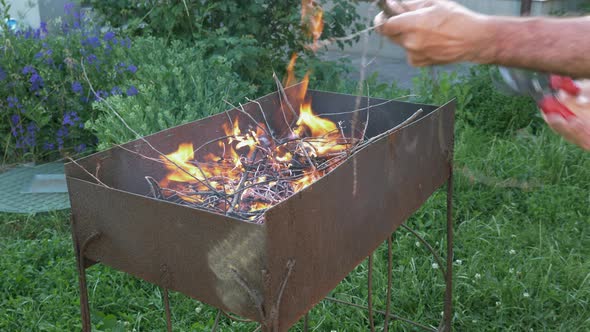 Man making fire flames for preparing grill. Flames from trees for grill or BBQ. Charcoal on fire alt