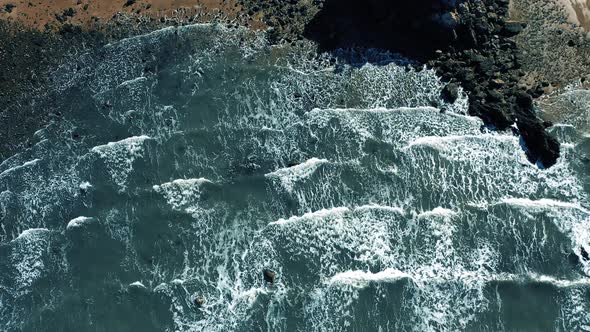 Stone beach and waves aerial shot alt