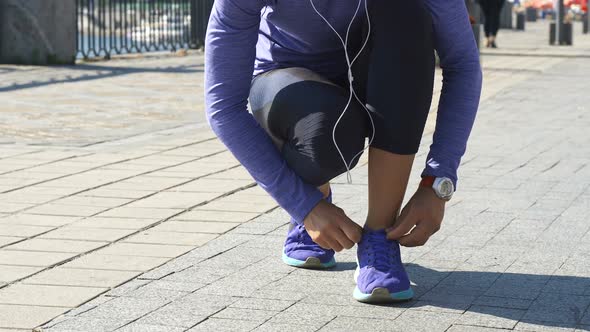 Woman Stops To Fix String on Sneakers alt