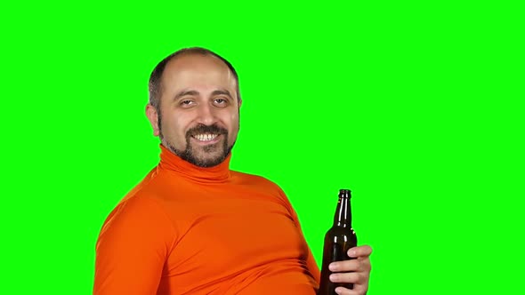 Caucasian Man Holds a Bottle of Beer in His Hands and Drinks with Pleasure, Green Screen. Slow alt