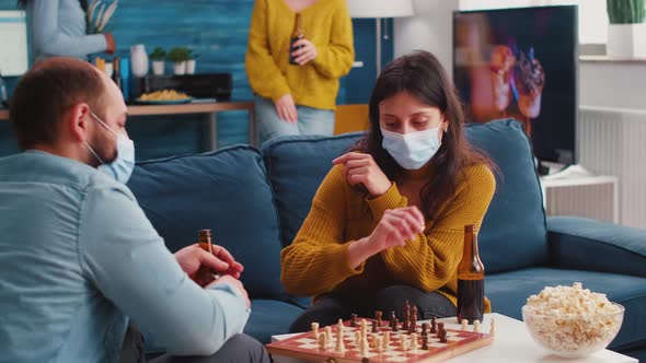 Friends Having Fun Playing Chess in Living Room During Global Pandemic alt