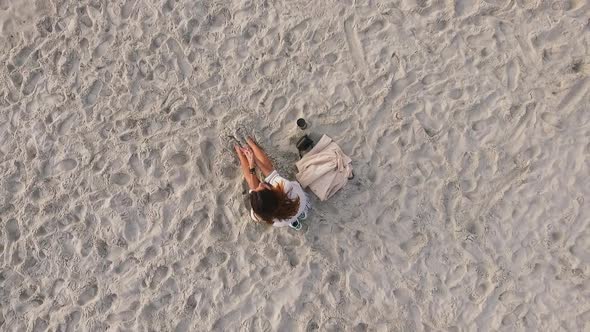 Footage From Above Romantic Tanned Girl with Long Dark Hair Sitting on Seashore Burying Feet Into alt