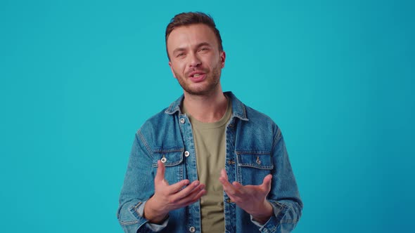 Young Caucasian Man Standing and Talking to Camera on Blue Background