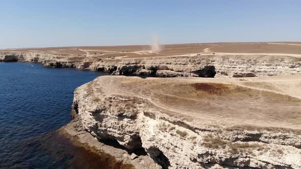 A Dusty Devil a Tornado on a Sandy Steep Bank Rages Through a Dry Bush alt