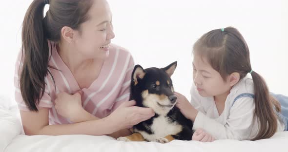 Mother and daughter playing with black dog on bed (9)