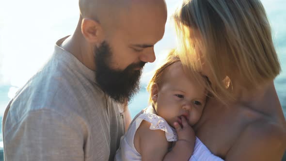 Portrait of a Young Married Couple and Their Cute Daughter Having Fun on the Beach at Sunrise alt