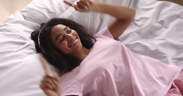 Young African American Woman Listening To Music in Bed alt
