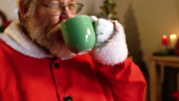 Santa claus relaxing on chair and having coffee alt