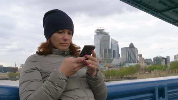 Girl Tourist Looks at the Phone in London, UK alt