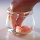 Hand taking artificial teeth out of glass of water. - VideoHive Item for Sale