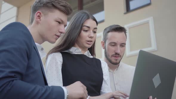 Portrait Cute Young Woman and Two Men in Formal Wear Discussing Project on the Laptop on the Terrace alt