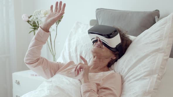 Elderly Patient Lying in Hospital Bed Doing Therapy Via VR Technology