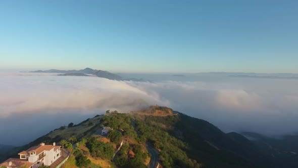 Aerial shot of villas and mountain tops in the clouds (Malibu Canyon, Monte Nido, California, USA) alt