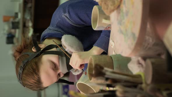Female Ceramist Paints a Clay Product
