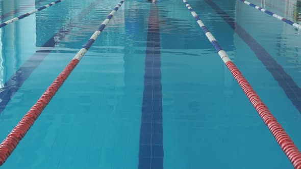 Young Girl in Goggles and Cap Swimming Crawl Stroke Style in the Blue Water Pool alt