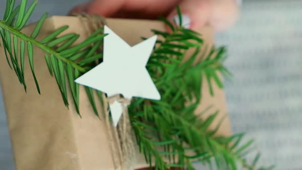 Woman Giving Box with New Year's Gifts Wrapped in Craft Paper and Decorated with Fir Branch alt