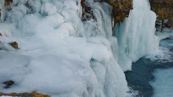 Closeup of Frozen Waterfall Bottom with Icy Rocks and Flowing Down Water alt
