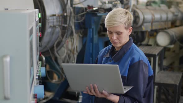  Female Factory Worker Using Laptop to Operate Machinery alt