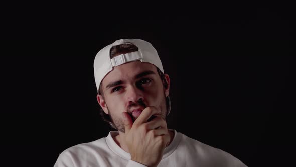 Trendy 20s Man thinking and rubbing chin, close, black background alt