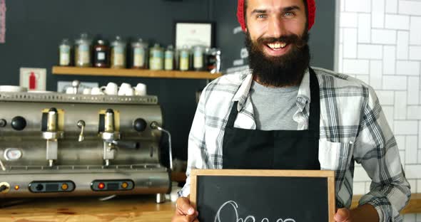 Portrait of waiter standing with open sign board alt