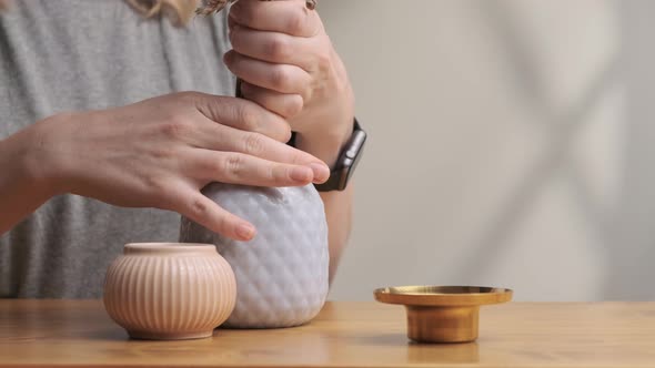 Woman in Gray T-shirt Puts Dried Flowers in Vase in Morning at Home. Lady Decorates Her Home in the alt
