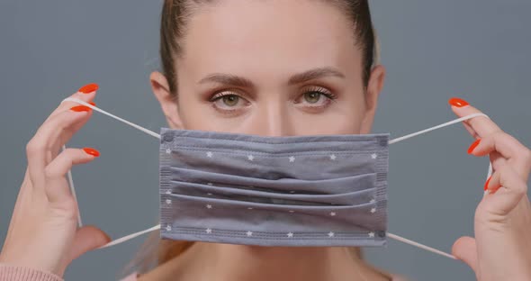 Lady Puts on Grey Polka Dot Protective Medical Mask Closeup alt