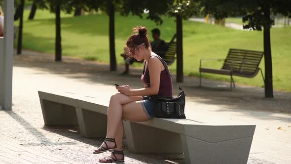 Young Woman In Park Sending SMS