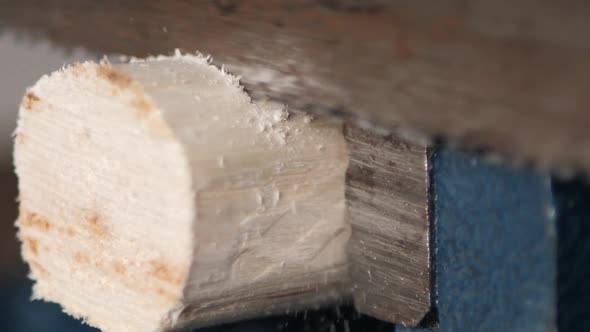 Extreme close up sawing a piece of a stick with a rusty saw in slow motion. alt